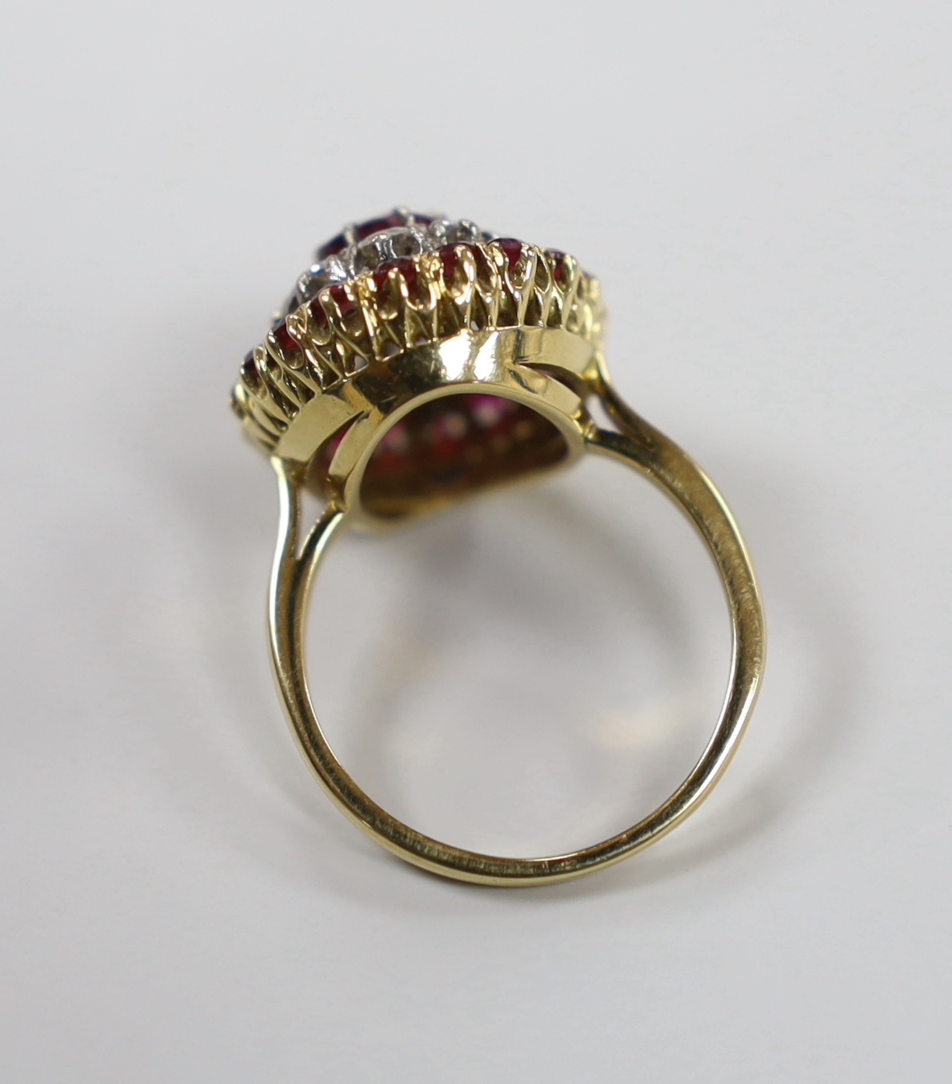 An 18ct, ruby and diamond cluster set oval cluster dress ring, size N/O, gross weight 6.3 grams.